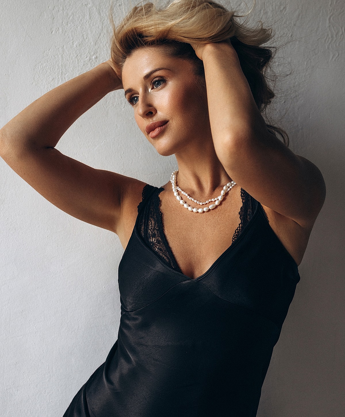 Woman in black dress with pearl necklace.