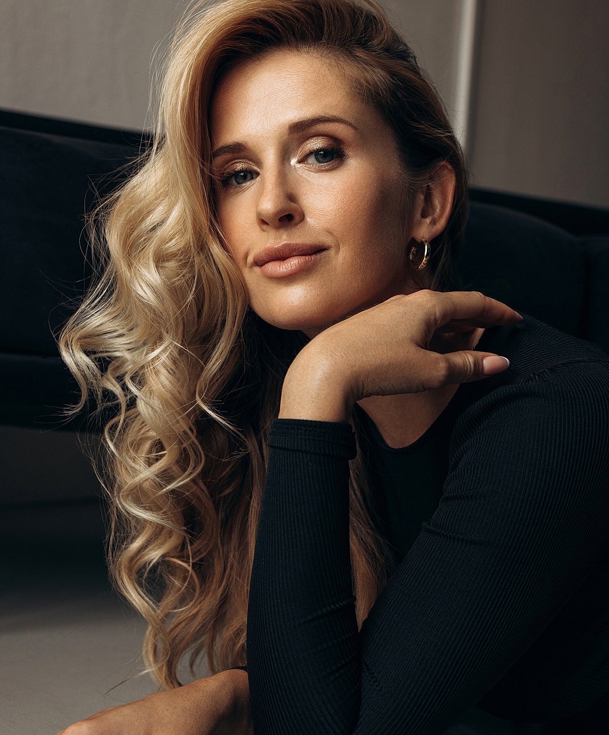 Woman with wavy blonde hair resting her chin.