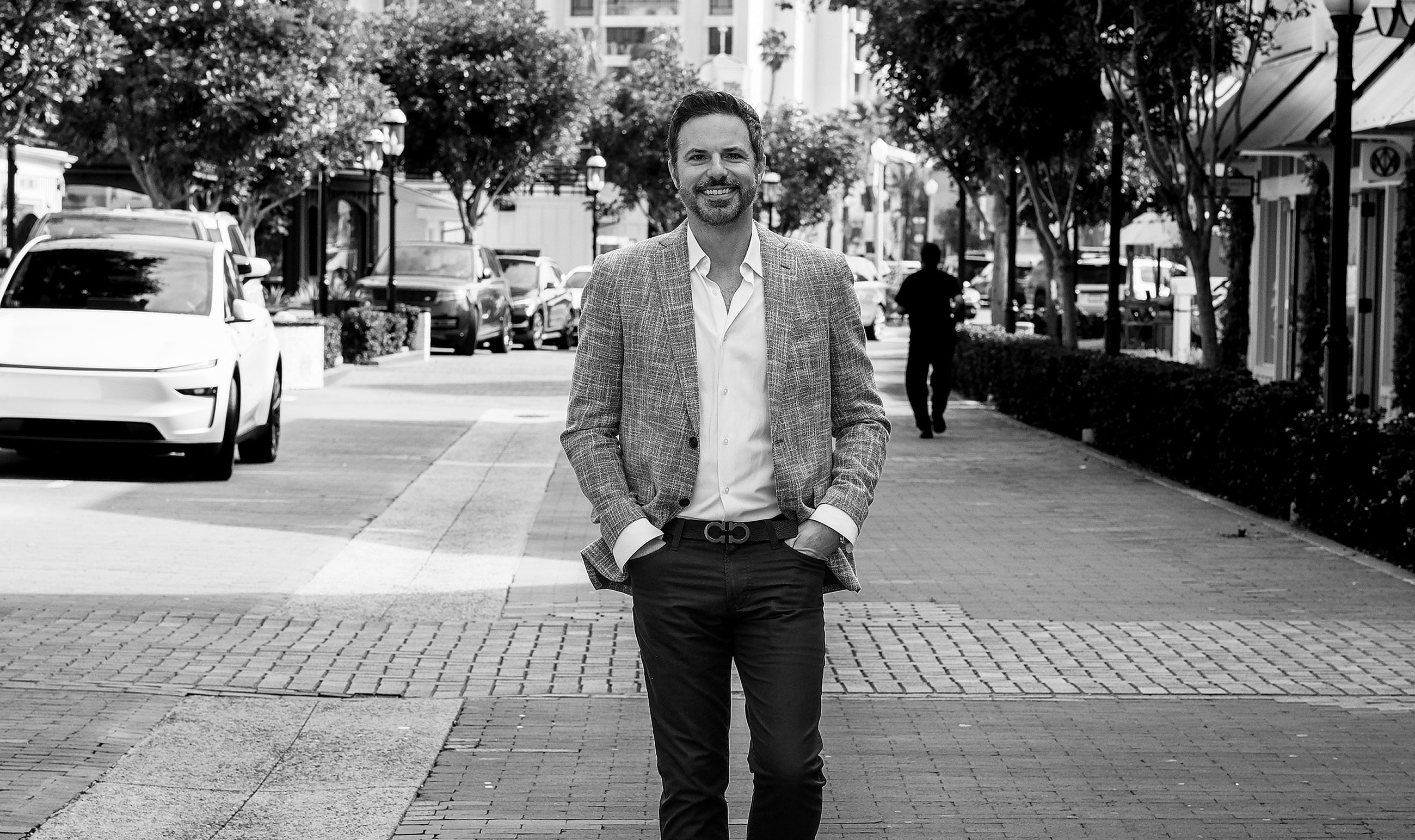 Smiling man walking down a city sidewalk.